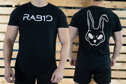 Two black t-shirts, one with 'RAB1D' text and the other with a rabbit logo, worn by two people against a wooden background.