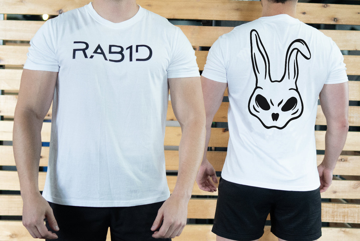 Two people wearing white t-shirts with 'RAB1D' on the front and a rabbit head design on the back, standing against a wooden background.