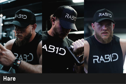 Man wearing a black cap and sleeveless shirt with 'RABID' branding, holding a dumbbell.