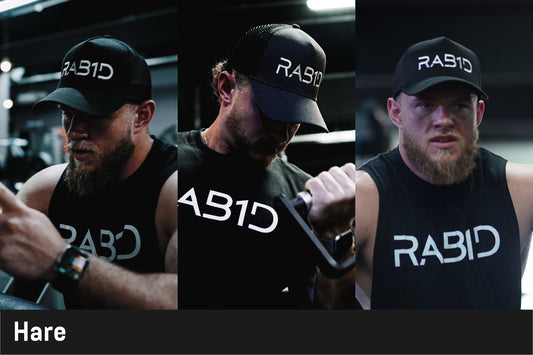 Man wearing a black cap and sleeveless shirt with 'RABID' branding, holding a dumbbell.